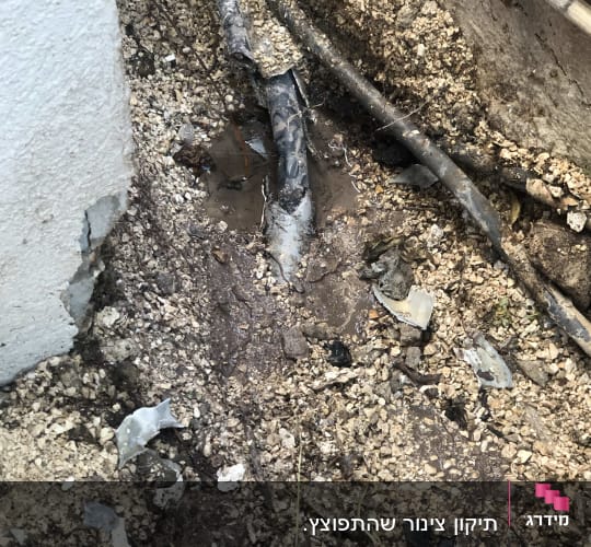צינור שבור באדמה עם מים מסביב